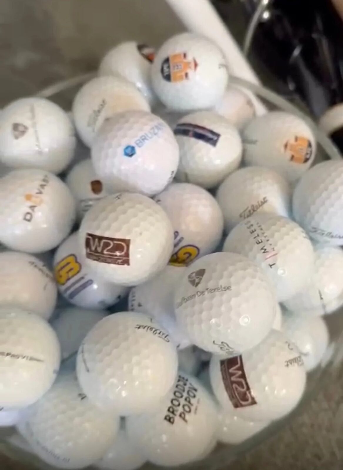 Bak vol bedrukte golfballen met verschillende bedrijfslogo’s