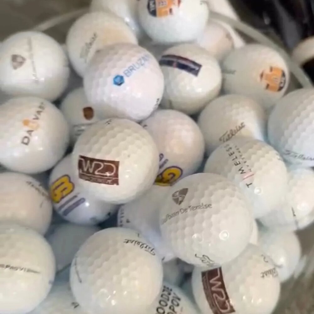 Emmer vol bedrukte golfballen met bedrijfslogo’s