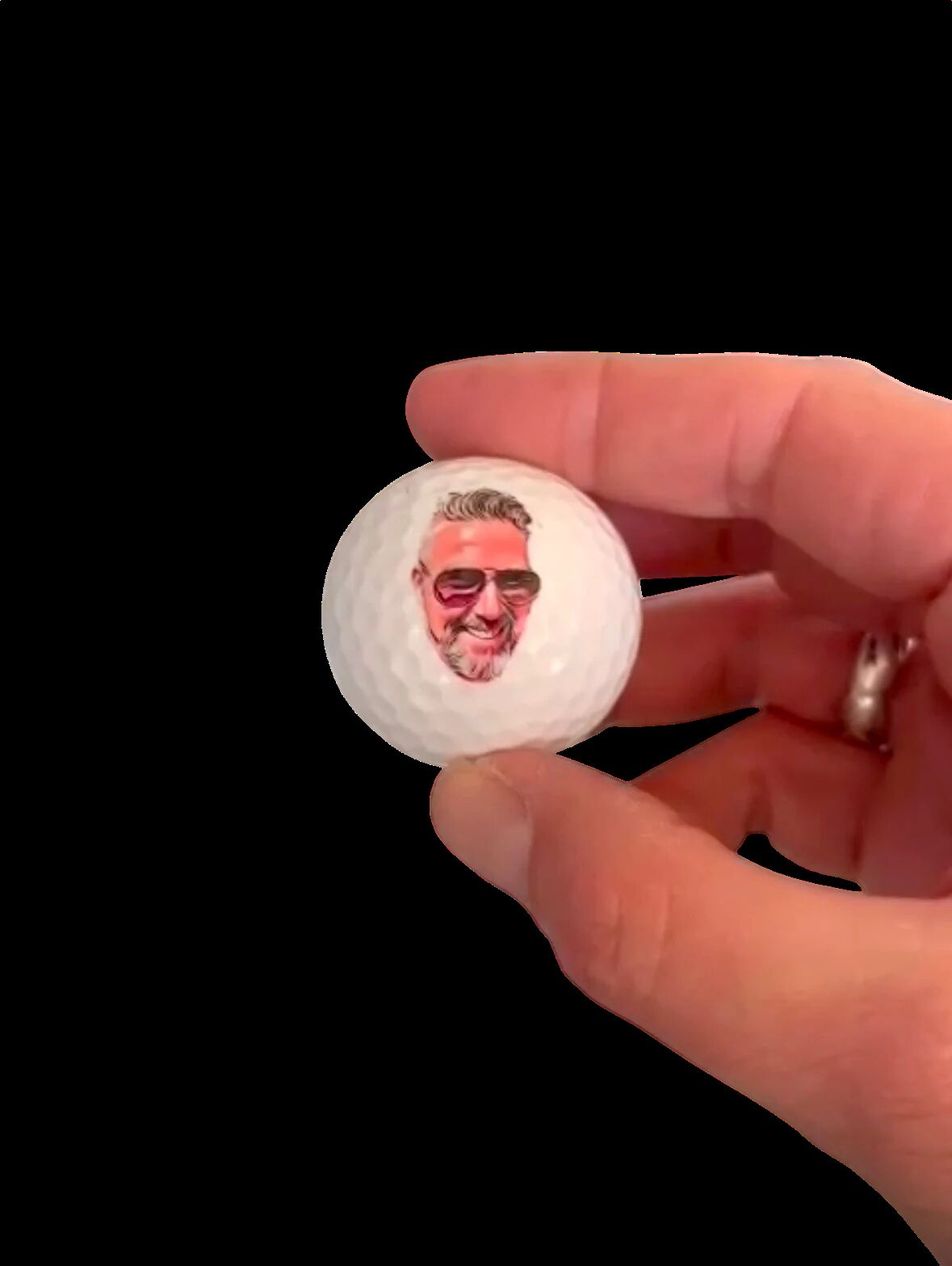A hand holding a golf ball with a photo of a face printed on it