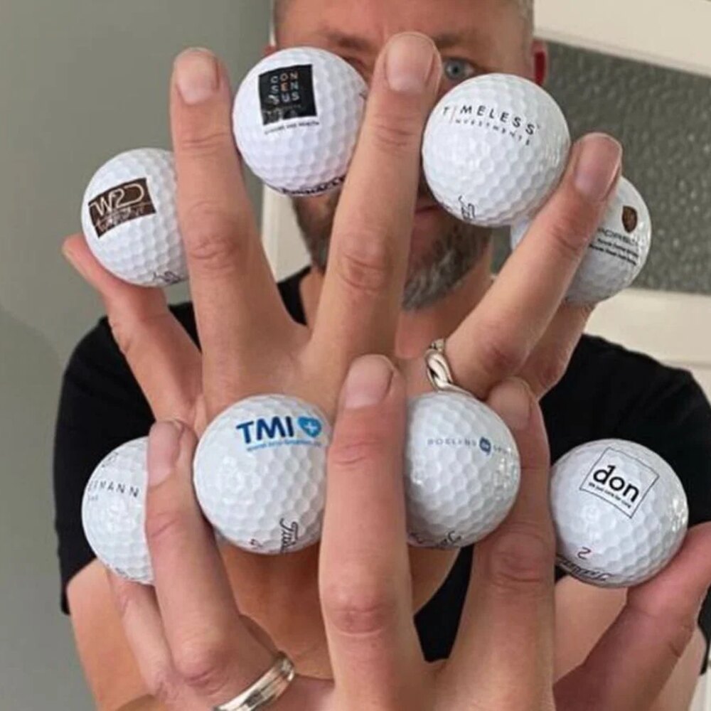 Hand met bedrukte golfballen met verschillende bedrijfslogo’s