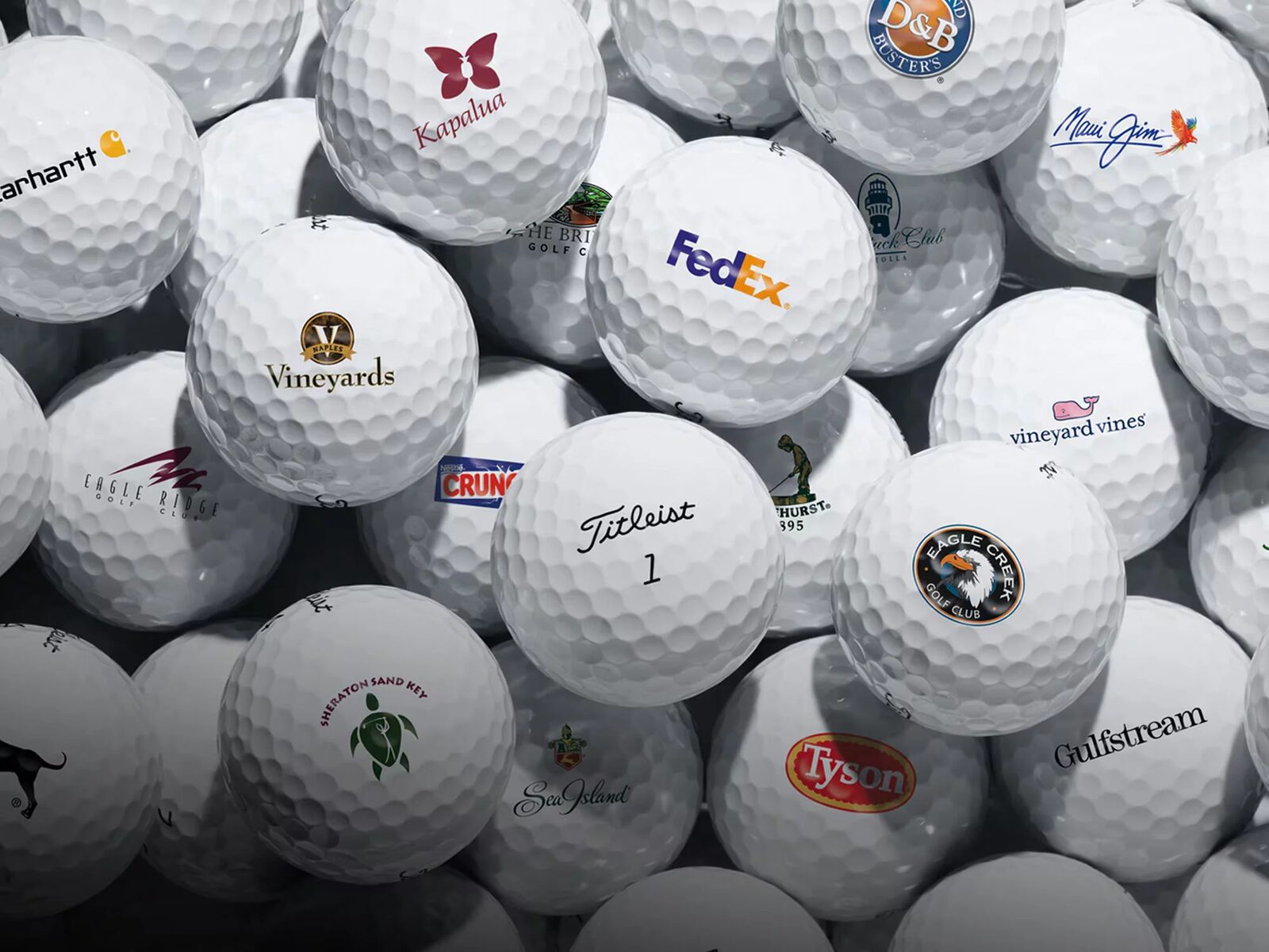 Stapel bedrukte golfballen met logo’s van uiteenlopende bedrijven