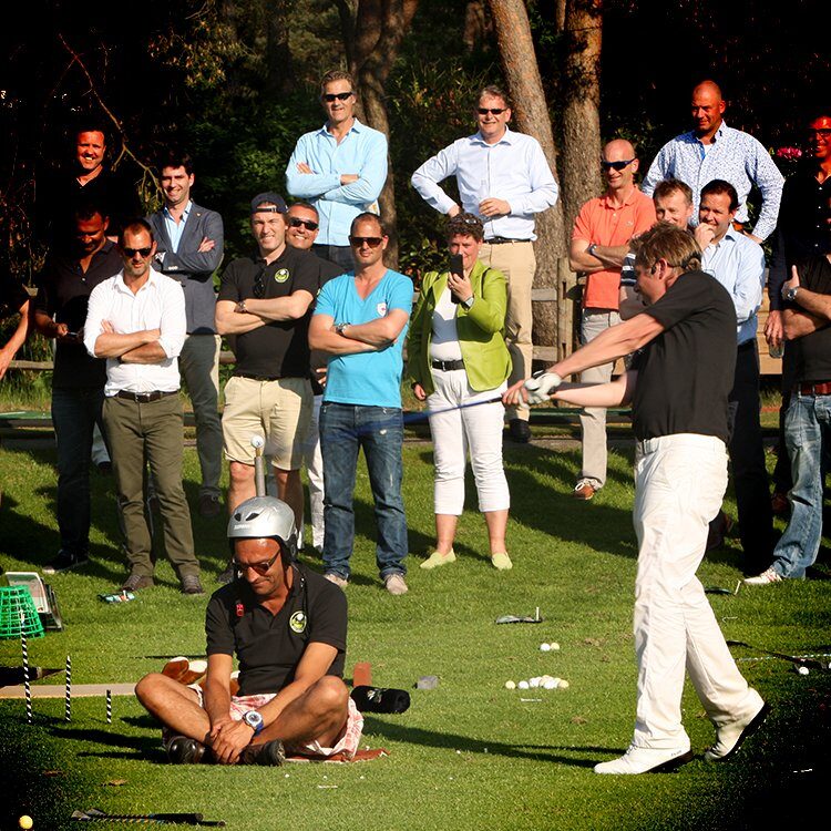 Mark Reynolds slaat af tijdens een golfshow op een event, omringd door genodigden