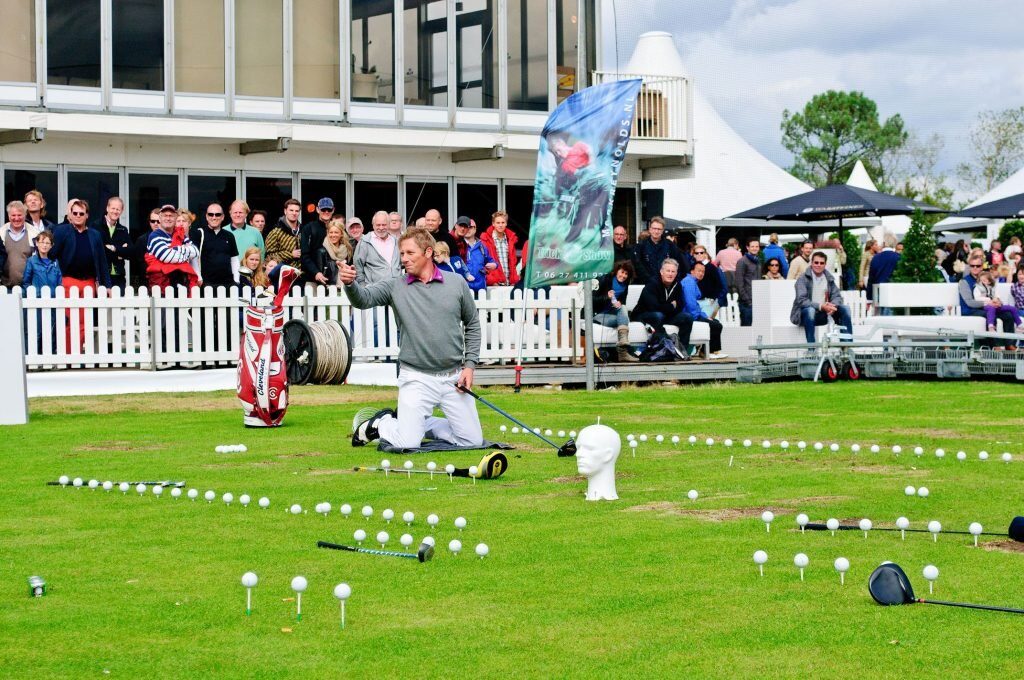 Golfdemonstratie voor een groep toeschouwers langs de afslagplaats