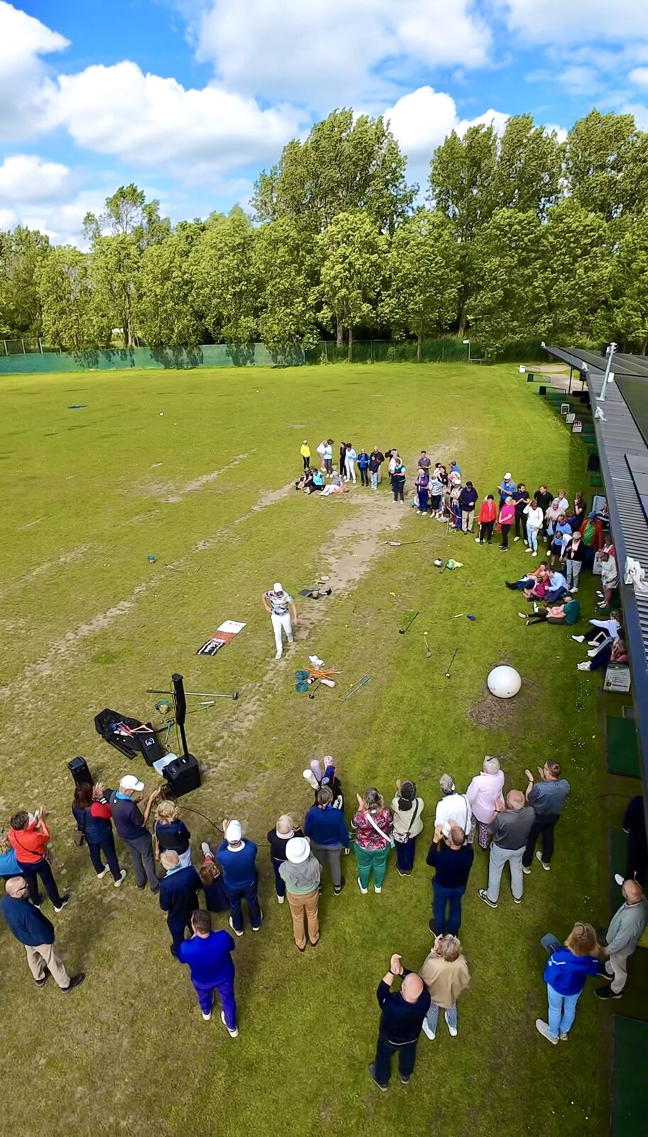 Publiek in een kring rond de afslagplaats tijdens een golfshow, van bovenaf gezien
